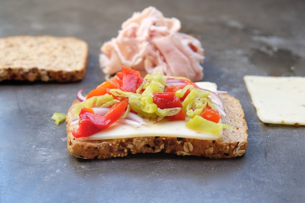 Grilled Turkey Pepper Jack Sandwich made with Dave's Killer Bread. There's roasted peppers & pepperoncini nestled in there! Find the recipe on Shutterbean.com!