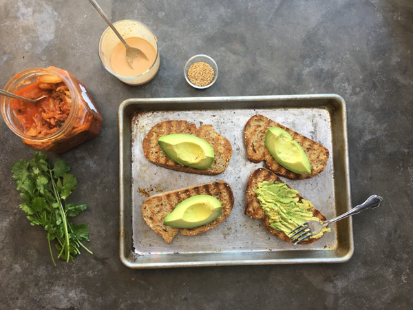 This isn't ordinary avocado toast. It's Avocado Kimchi Toast with a spicy tahini drizzle. Find recipe at Shutterbean.com